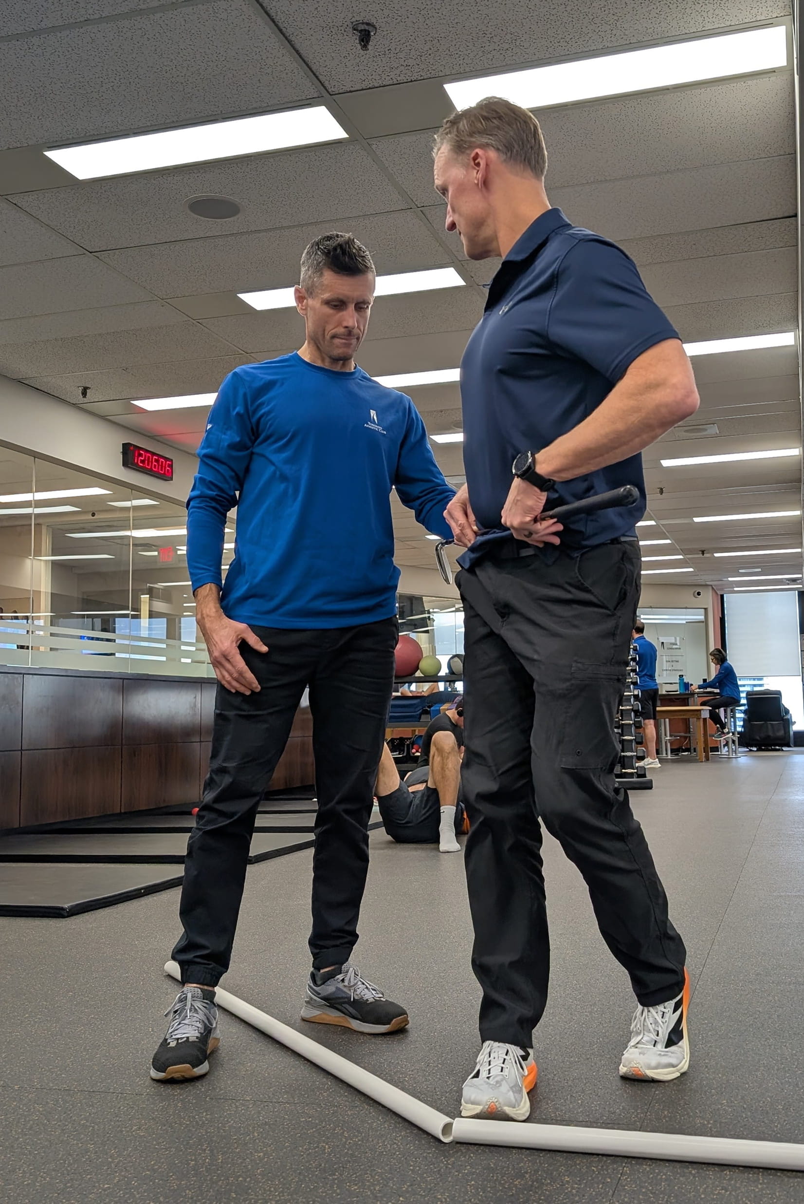 TPI-certified trainer coaching a golfer on hip rotation and body mechanics on the gym floor, representing the integrated golf fitness and movement training at the Adelaide Club Gym and Sim program